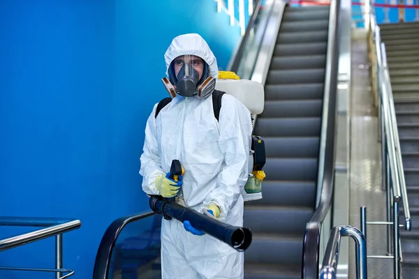Retrato de desinfectante de confianza en traje con rociador en escalera mecánica —  Fotos de Stock