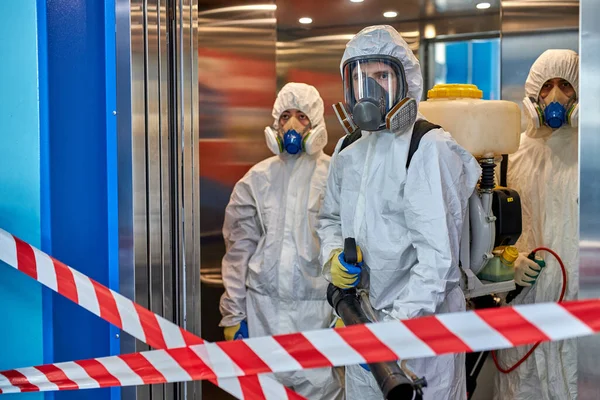 People in hazmats making cleaning in apartment building — Stock Photo, Image