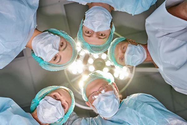 view from below of professional experienced surgeons with medical tools during operation