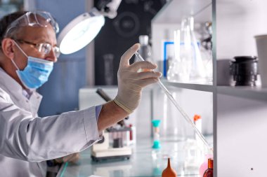 Yeni korona virüsünün laboratuvar analizinde kıdemli erkek bilim adamının yan görüntüsü