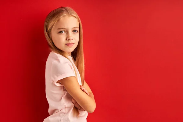 Tímido confiado niña caucásica aislado sobre rojo estudio fondo — Foto de Stock