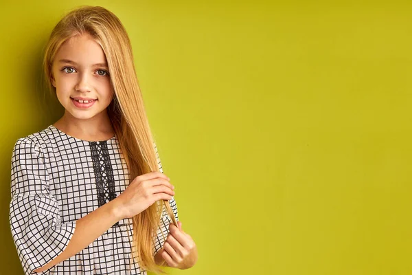 Schattig kind meisje is het aanraken van haar lang blond haar — Stockfoto