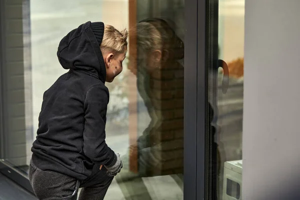Bedelaar straat jongen leunde op raam van voedsel winkel — Stockfoto