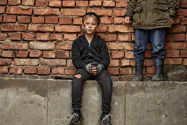 Ongelukkige vermoeide jongen zit op het beton buiten kijken naar camera — Stockfoto