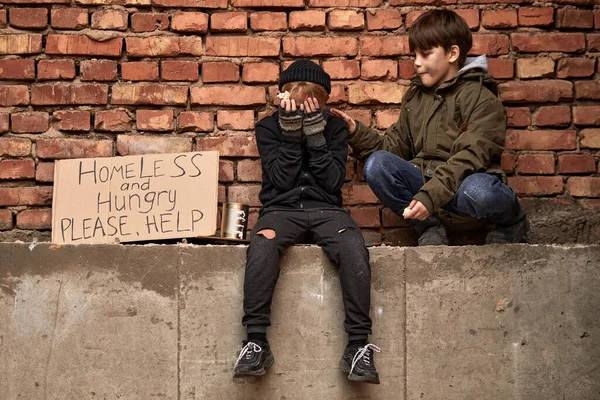 当他的朋友平静下来支持他时，沮丧的街头男孩哭着坐在那里 — 图库照片