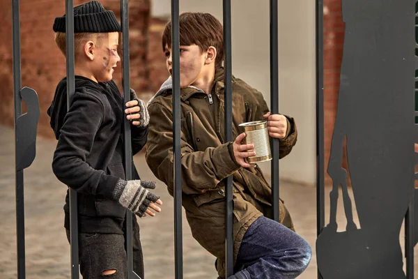 Two homeless kids ask for money through bars — Stock Photo, Image