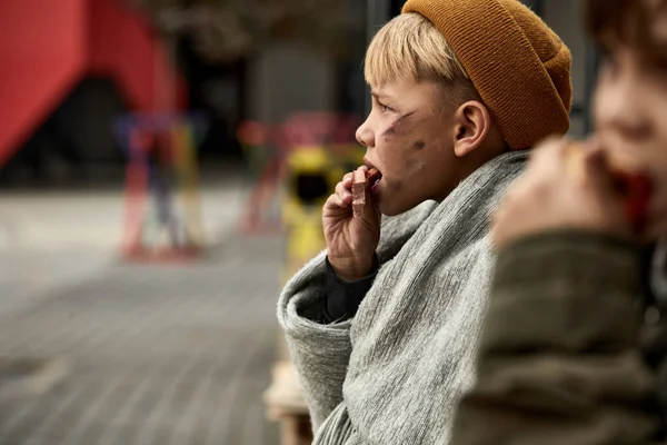 Zijaanzicht op dakloze jongen eten buiten — Stockfoto