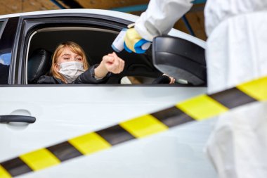 Tıbbi işçiler termometreyle araba sıcaklığında başka birini alıyorlar.