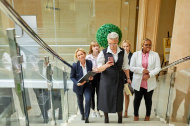 Çeşitli bayanlar takımı toplantıdan sonra merdivenleri tırmanır.