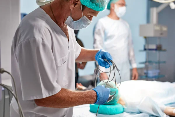 Vue latérale sur le matériel de maintien du chirurgien adulte aîné à l'hôpital — Photo