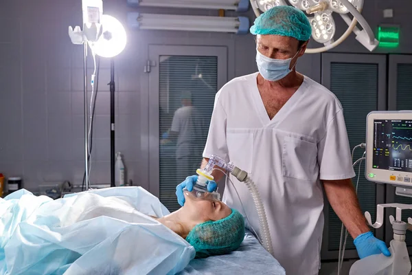 Уверенный в себе хирург дает кислородную маску пациенту — стоковое фото