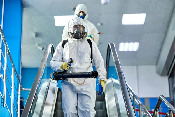 Disinfettanti in tute protettive da virus e maschera disinfettante edifici di coronavirus con lo spruzzatore — Foto Stock
