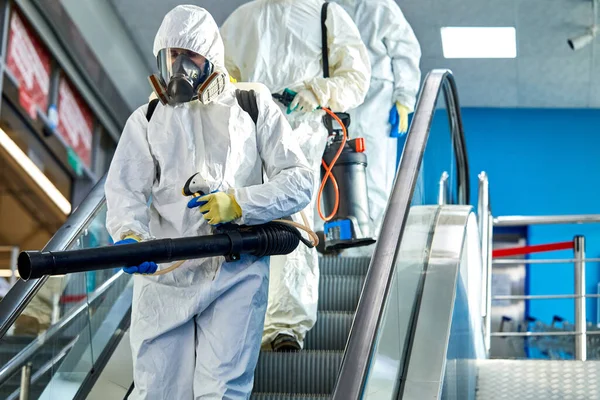 Les gens en combinaison de protection contre le virus vont nettoyer désinfecter le bâtiment — Photo