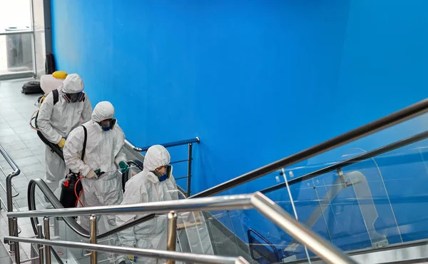 Dezynfektor w kombinezonach ochronnych dezynfekujący schody rozpylaczami — Zdjęcie stockowe