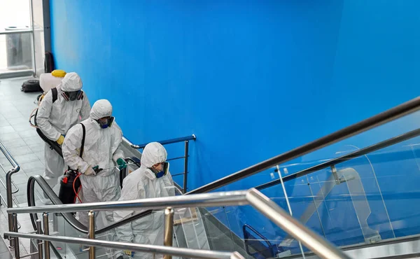 Desinfectante con trajes protectores desinfectando escaleras con productos químicos en aerosol — Foto de Stock