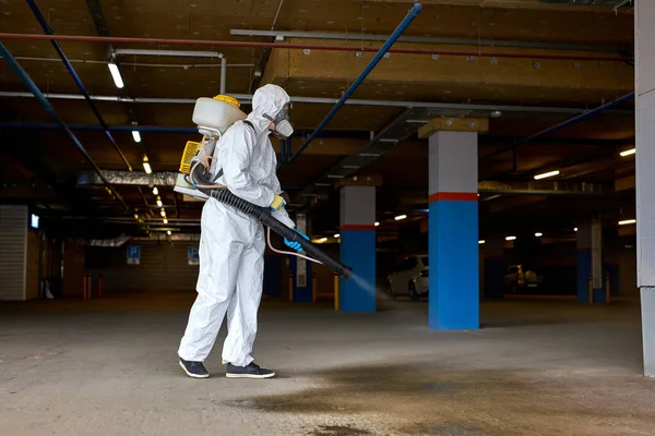 Professional disinfecor in protective suit wearing face mask making disinfection —  Fotos de Stock