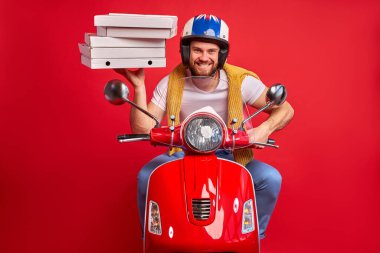 Beyaz bir erkek motosiklet kullanıyor. Yığınla pizza getiriyor.