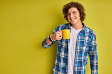 Sabahları kareli tişörtlü, bir fincan çayla mutlu beyaz çocuk.