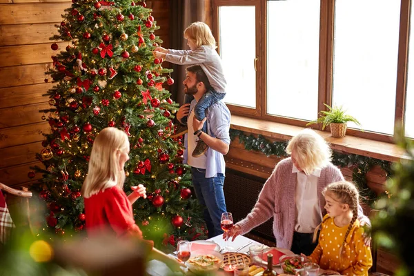 Feliz familia decorando el árbol de Navidad en la sala de estar — Foto de Stock