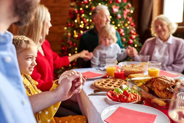 holidays and religious concept -family having christmas dinner and praying before meal