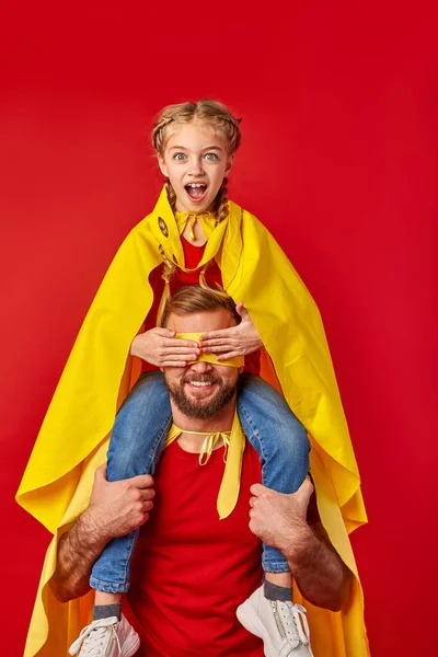 Fille surprise s'assoit sur le cou de père fermant les yeux, super héros — Photo