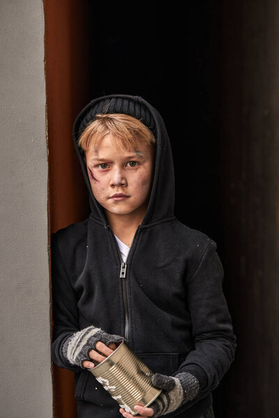 portrait of poor little orphanage boy with jar for money donation