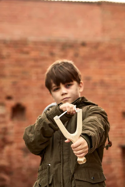 focus on slingshot in street boys hands to shoot at a target outdoors