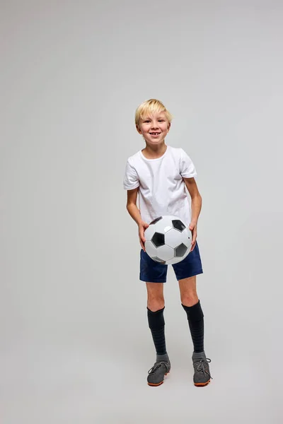 Menino esportivo em sportswear segurando bola de futebol, posando no estúdio — Fotografia de Stock