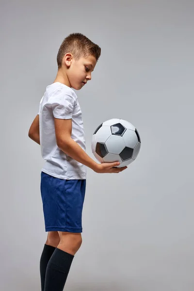 Menino de futebol em sportswear segurando bola de futebol, posando no estúdio — Fotografia de Stock