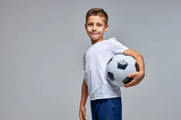 Menino esportivo em sportswear segurando bola de futebol, posando no estúdio — Fotografia de Stock