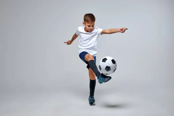 Jovem caucasiano menino com bola de futebol fazendo voar chute — Fotografia de Stock
