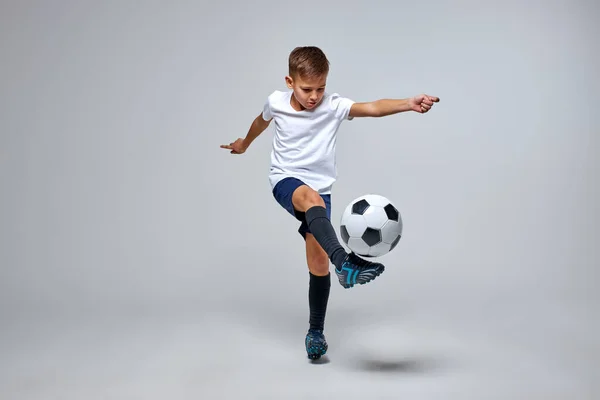 Futbol topuyla uçan tekme atan beyaz bir çocuk.