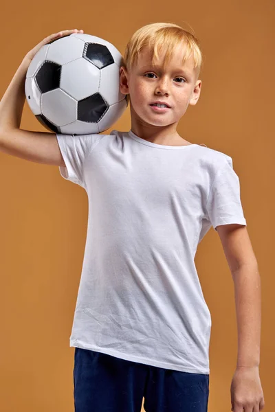 年轻的足球运动员,肩膀上有球摆出姿势 — 图库照片