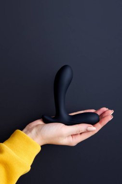 Elinde siyah vibratör tutan bir kadının kesilmiş fotoğrafı.