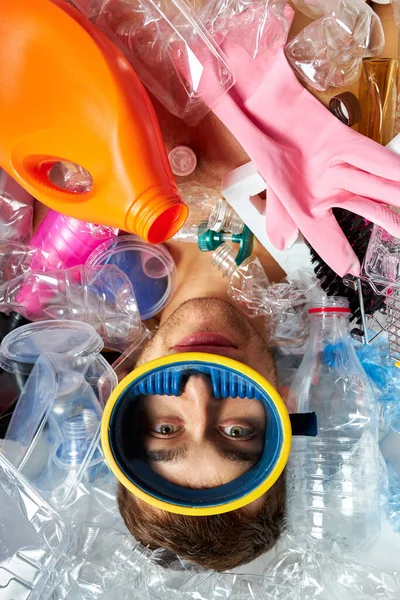 Ung kaukasisk man på bakgrunden av tomma plastflaskor och skräp — Stockfoto