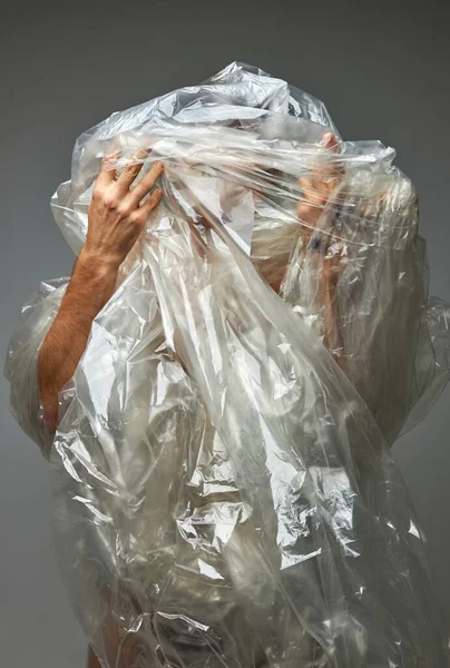 Oigenkännlig person insvept i transparent polyetylen plastpåse — Stockfoto
