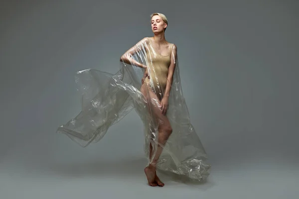 Fullängdare porträtt av smal halvnaken kvinna i body suit poserar med transparent plastpåse — Stockfoto
