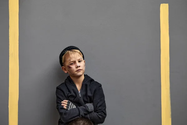 Ongelukkige kind jongen in vuile kleren staan met gekruiste armen kijken naar camera — Stockfoto