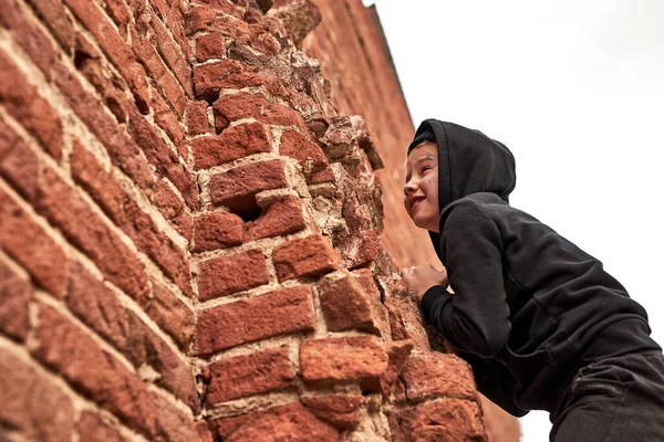 Street child boy is playing, climbing the building — Stock Photo, Image