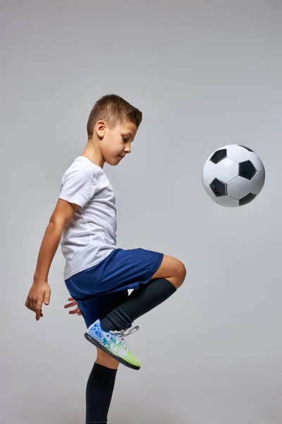 Esportivo caucasiano criança menino profissionalmente formação com bola de futebol no estúdio — Fotografia de Stock