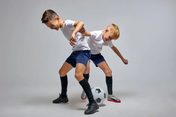 Crianças da escola adolescente jogando futebol em estúdio, prática driblando habilidades — Fotografia de Stock