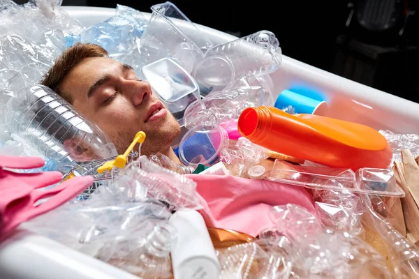 Naken man ligger anong tomma plastflaskor och skräp — Stockfoto