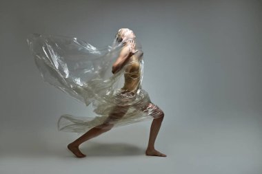 İşkence görmüş, susuz kalmış, hasta model kadın elinde plastik bir çantayla dikiliyor.