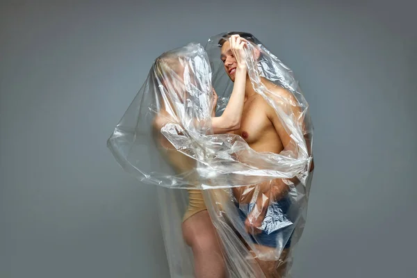 Halvnakna par poserar insvept i plastavfall, plastpåse — Stockfoto