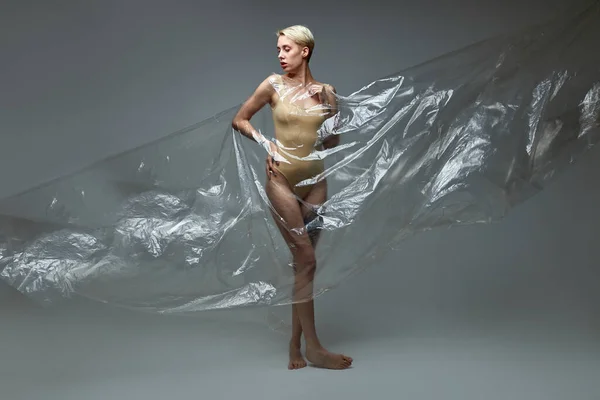 Smal kvinnlig modell poserar med transparent plastpåse i studio — Stockfoto