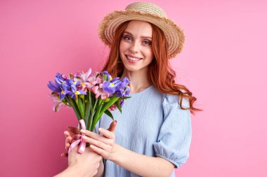 Minnettar kızıl saçlı kadın, taliplerinden çiçek aldığı için mutlu.