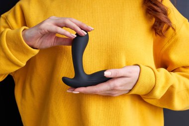 Elinde siyah vibratör tutan bir kadının kesilmiş fotoğrafı.