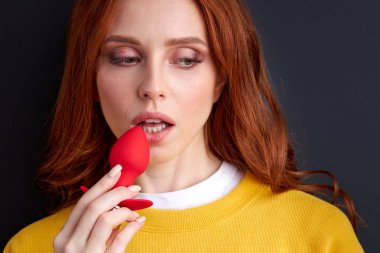 redhead female posing with silicone red butt plug