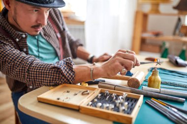 Kuyumcu kuyumcu aletlerini kullanarak mücevherleri onarıyor.