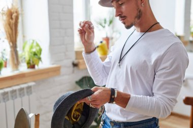 Erkek terzi şapka diker, iğne ve iplik kullanır.